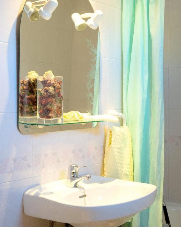 Lavabo pequeño con espejo, dispensadores de jabón y una toalla a rayas junto a una cortina de ducha.