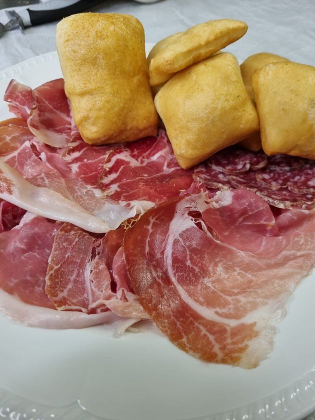 Piatto di prosciutto crudo affettato con cubetti di pane fritto dorato.
