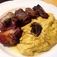 Pezzi di carne grigliata con glassa serviti su polenta gialla cremosa