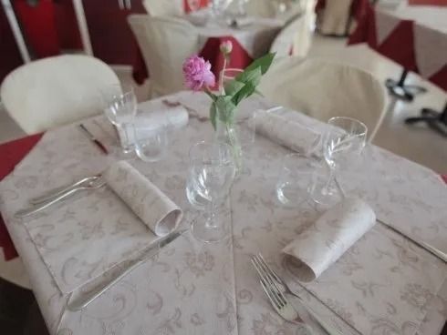 Tavolo da pranzo rotondo apparecchiato con tovaglioli arrotolati