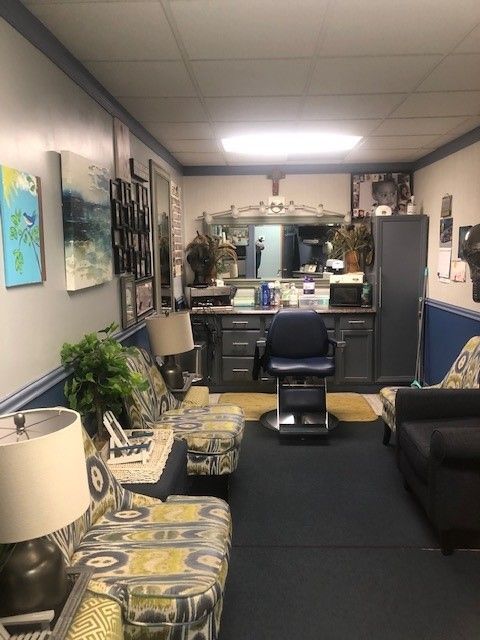 Barbershop interior with blue walls, a dark floor, chairs, and a mirror.