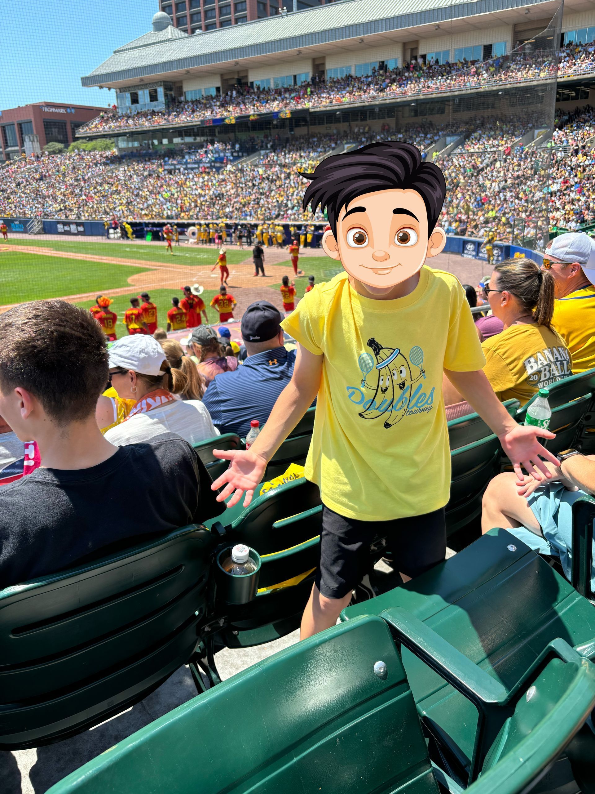 A young boy in a yellow shirt is standing in the stands at a baseball game.