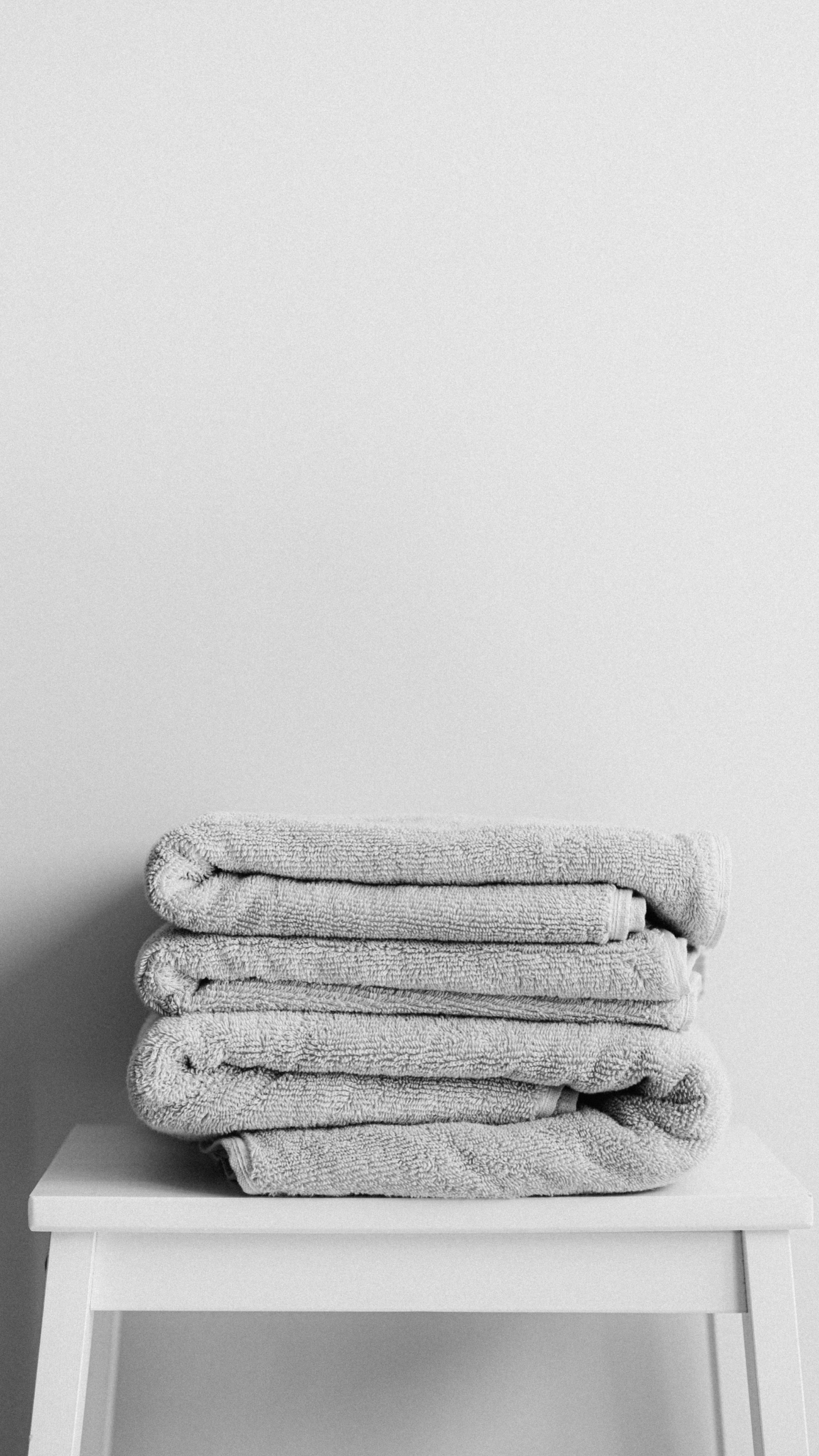 A stack of towels is sitting on top of a white stool.