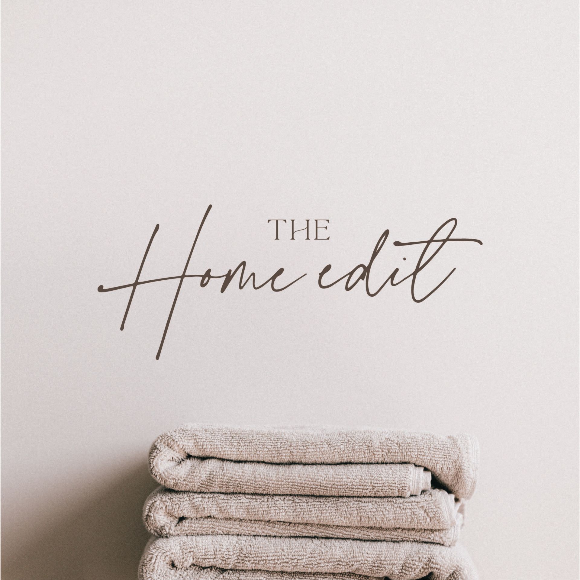 A stack of towels is sitting in front of a wall that says the home edit.