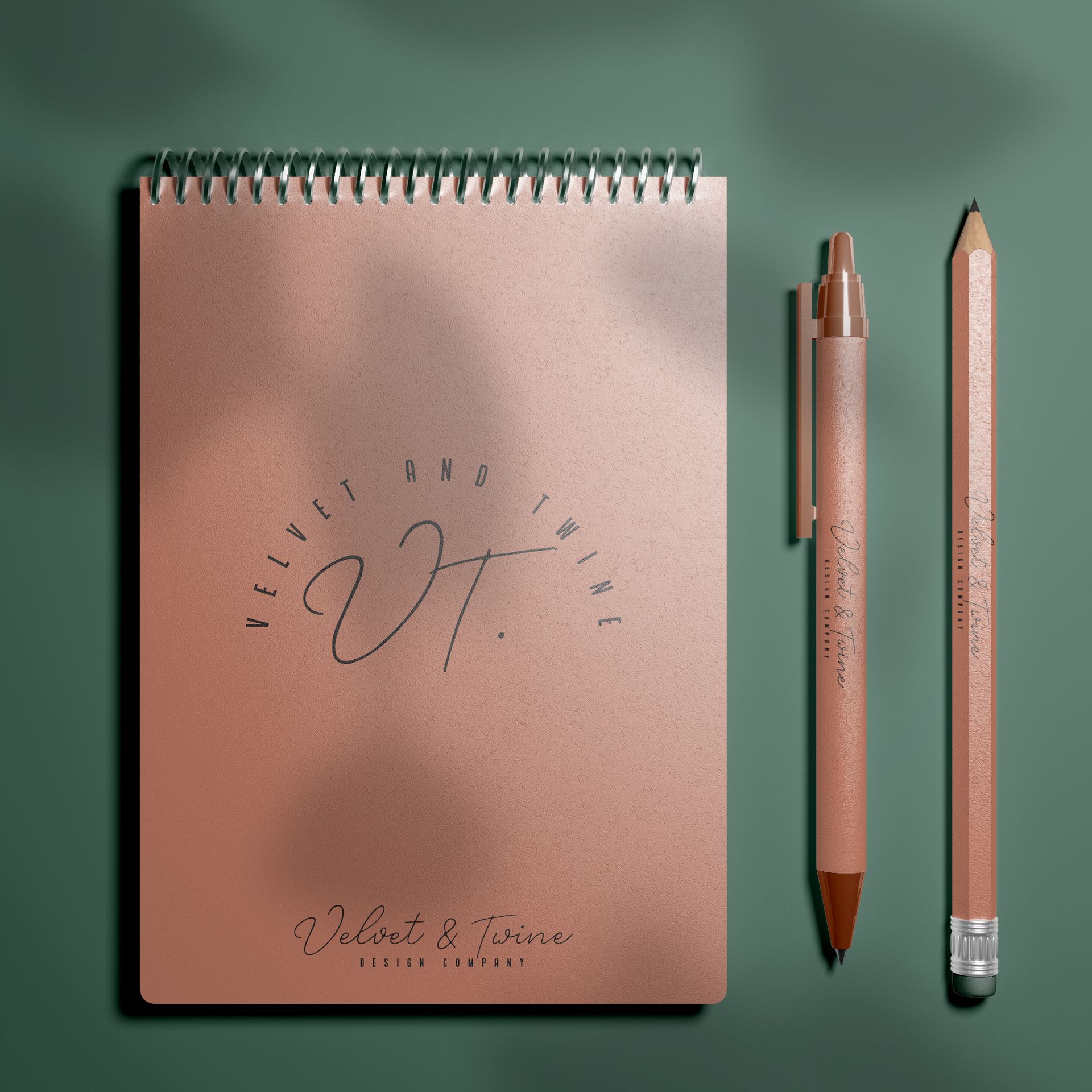 A notebook and two pens are on a green surface