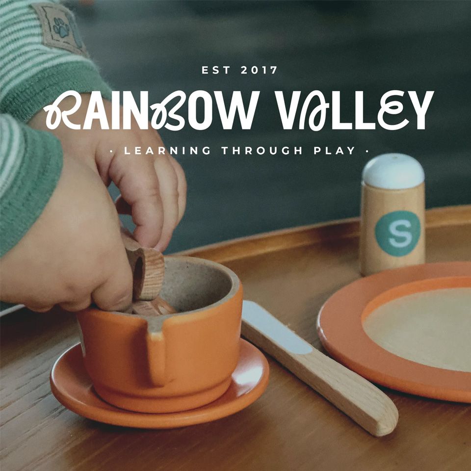 A baby playing with a wooden dish set.