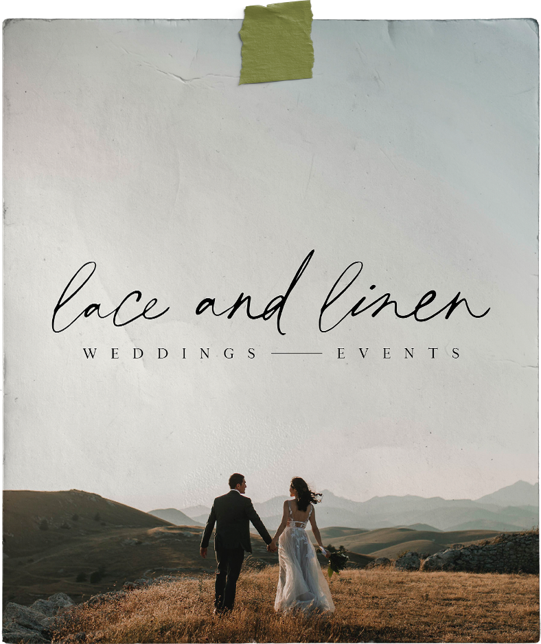 A bride and groom are walking through a field holding hands.