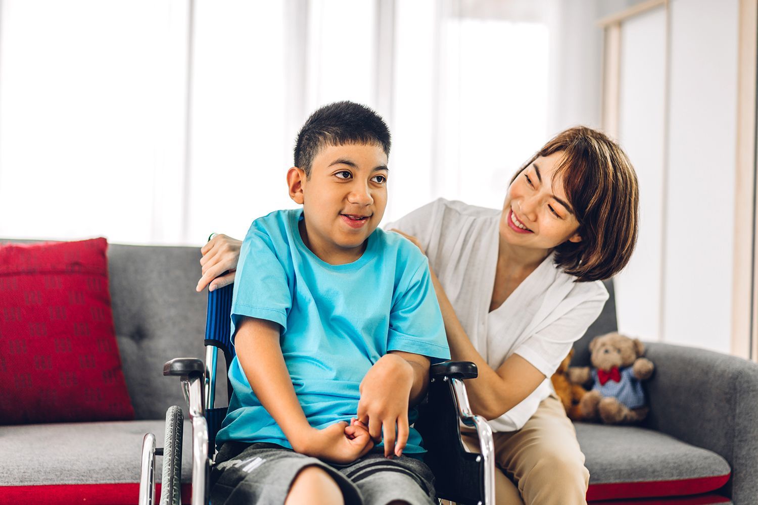 Carer spending quality time with a disabled child seated in a wheelchair at home. Carer spending quality time with a disabled child seated in a wheelchair at home.