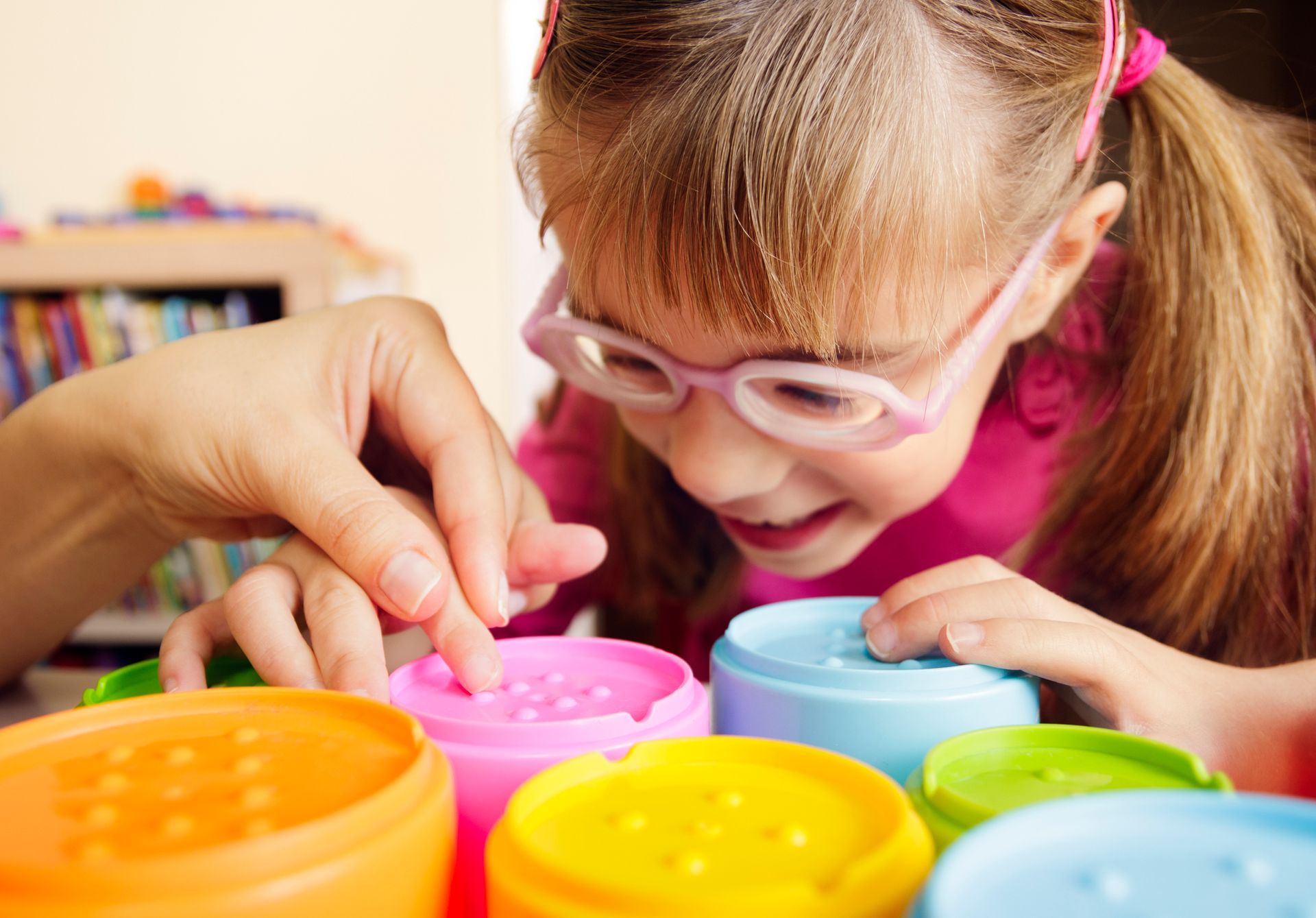 A little girl wearing glasses is playing with colorful toys.