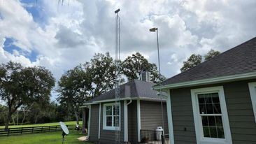 Two towers extend above a house with gray siding. Cloudy sky backdrop.
