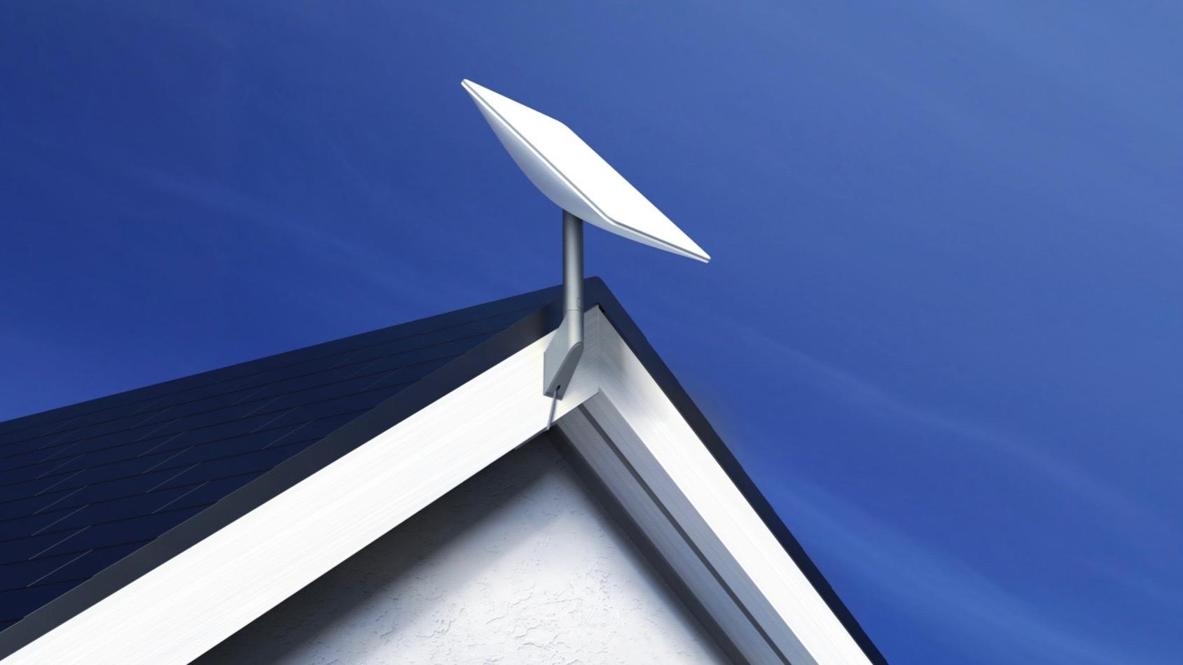 White satellite dish mounted on a house roof, against a blue sky.