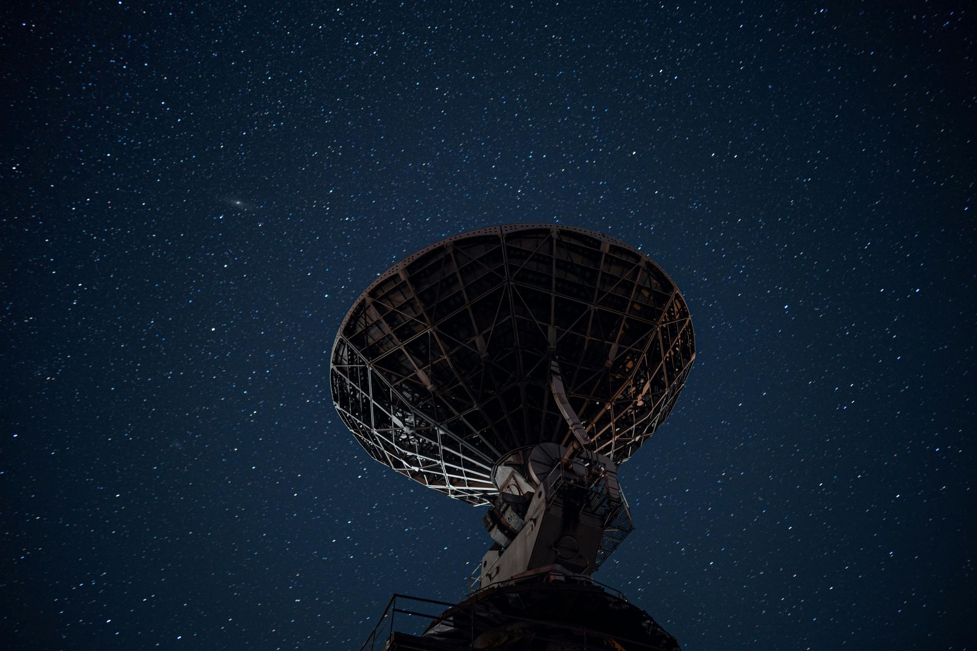 Large satellite dish under a dark, starry night sky.
