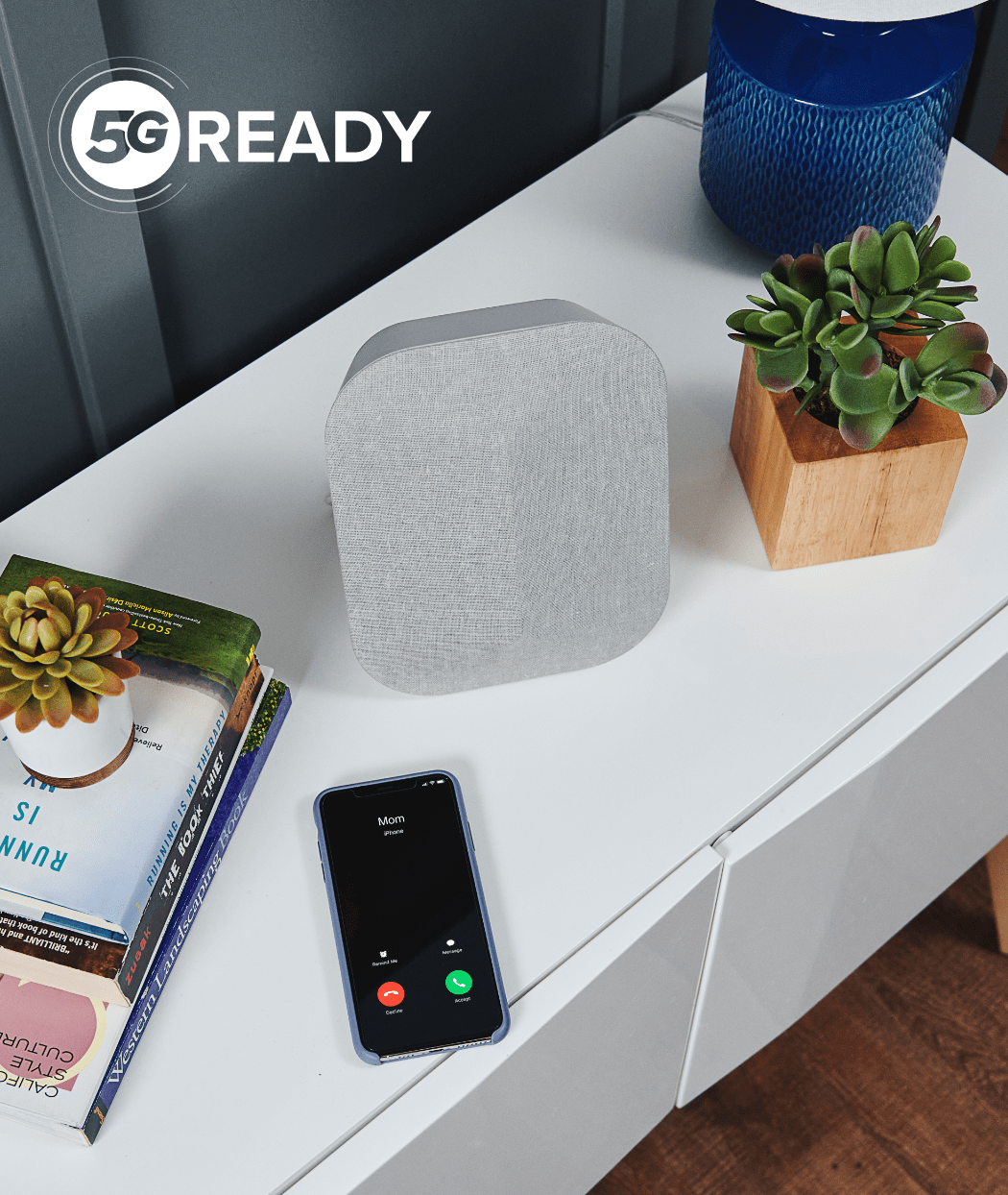 A light gray 5G-ready home device on a white table next to a phone with an incoming call.