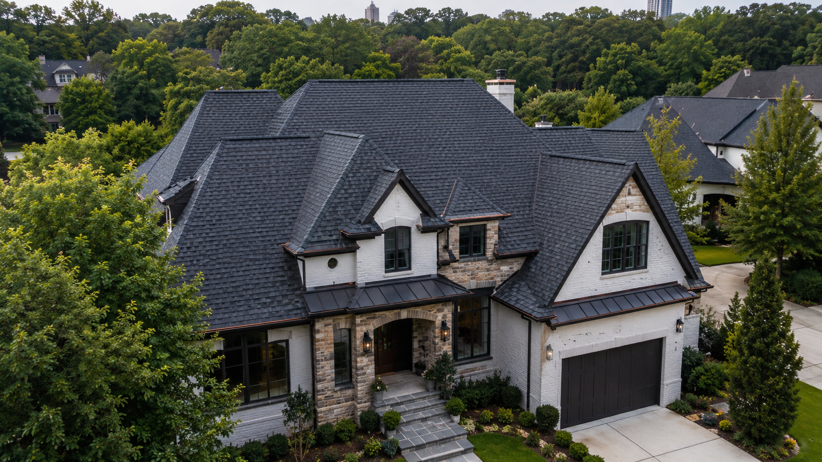 Suburban house roof with dark gray shingles and a beige gable under a cloudy sky