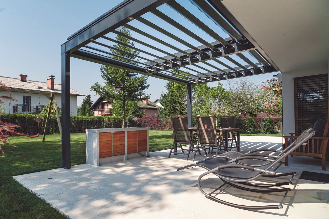 A patio with chairs and a table under a pergola.