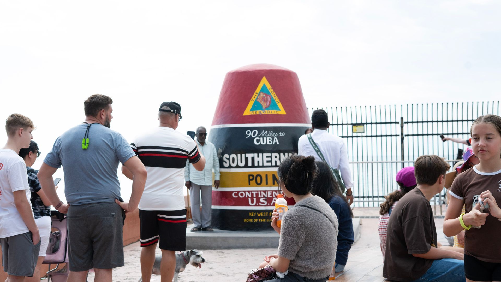 Tourists visiting the iconic Southernmost Point buoy in Key West, marking 90 miles to Cuba and the southern tip of the continental United States