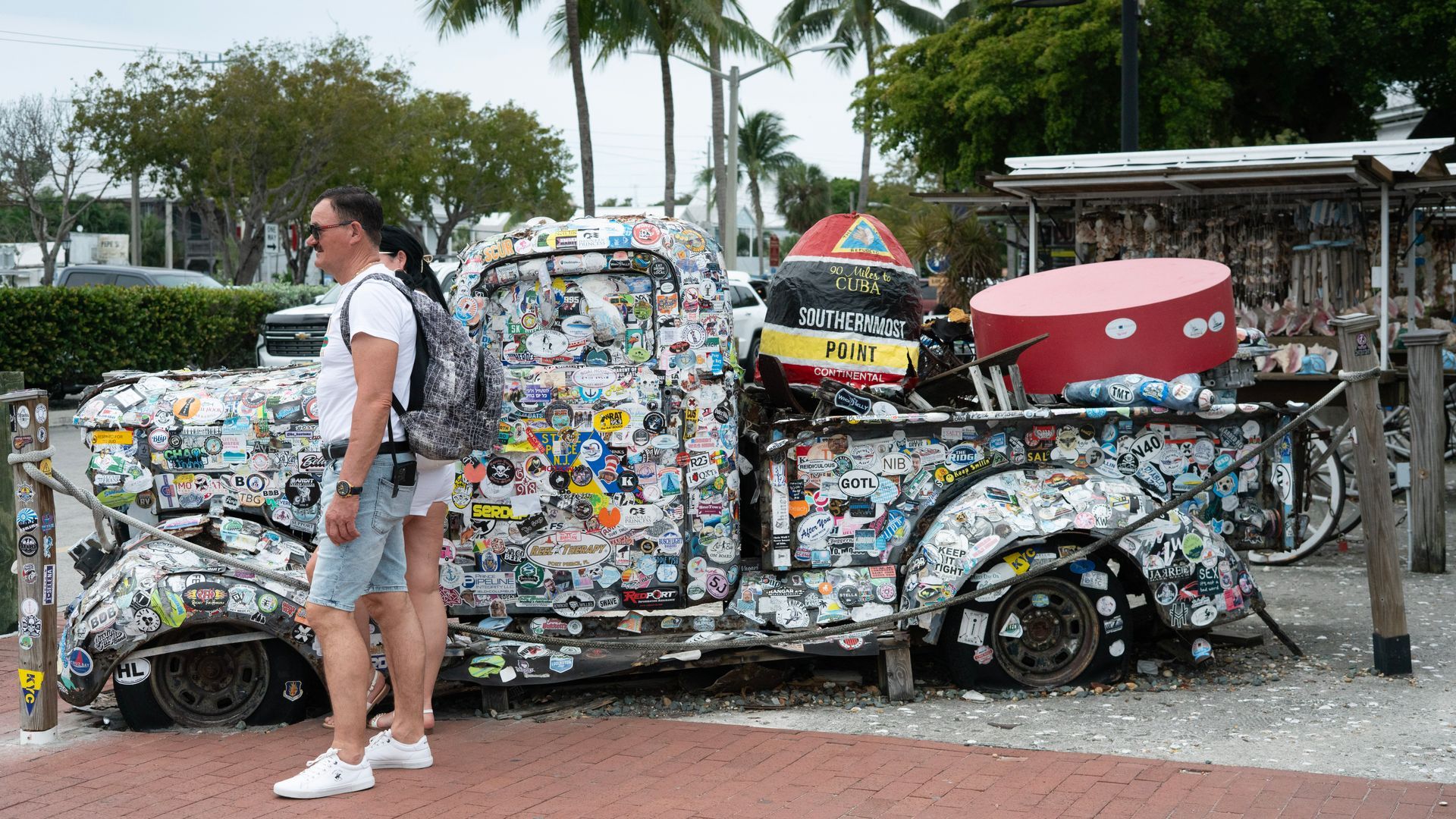 Vintage sticker-covered truck in Key West with a replica of the Southernmost Point Buoy, a quirky photo spot near the famous marina markets