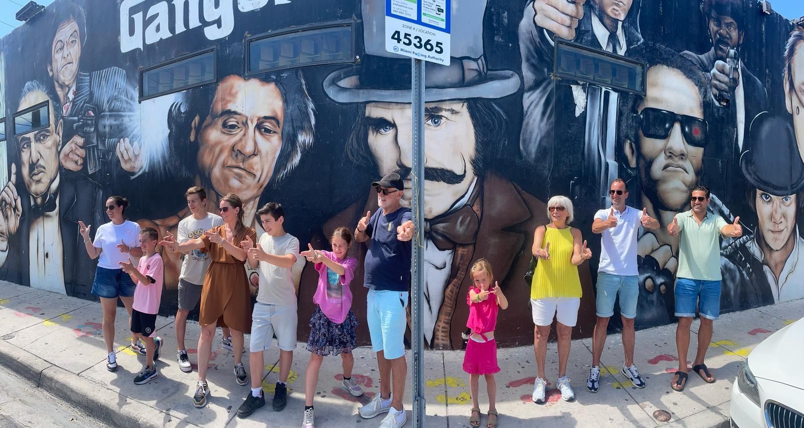 Passengers in Wynwood Walls taking a Selfie with the Gangster Mural Behind them on the Miami Tour Bus, one of the best Miami Tour