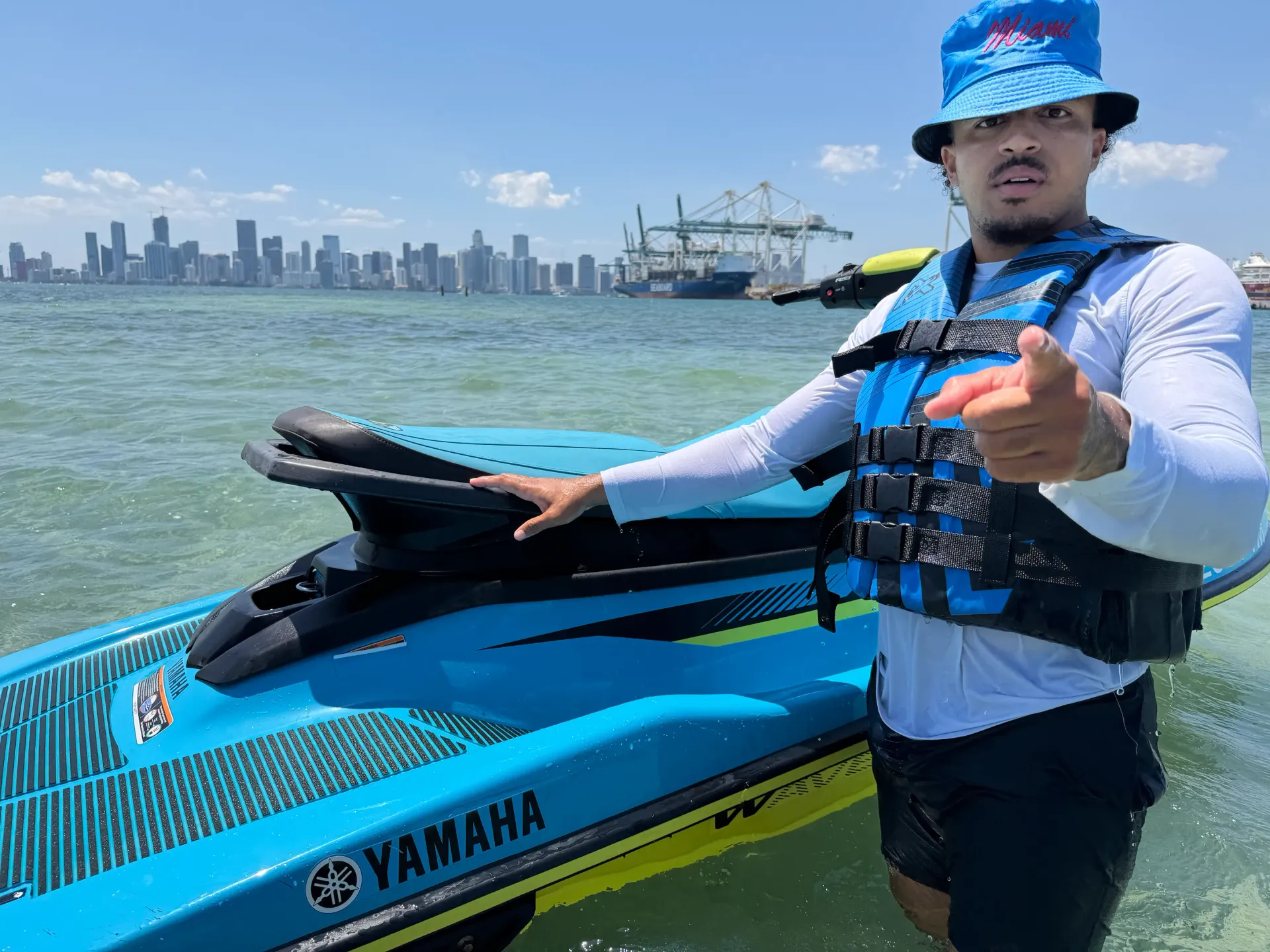 Jet ski rider standing beside a Yamaha WaveRunner with views of the Downtown Miami skyline across Biscayne Bay