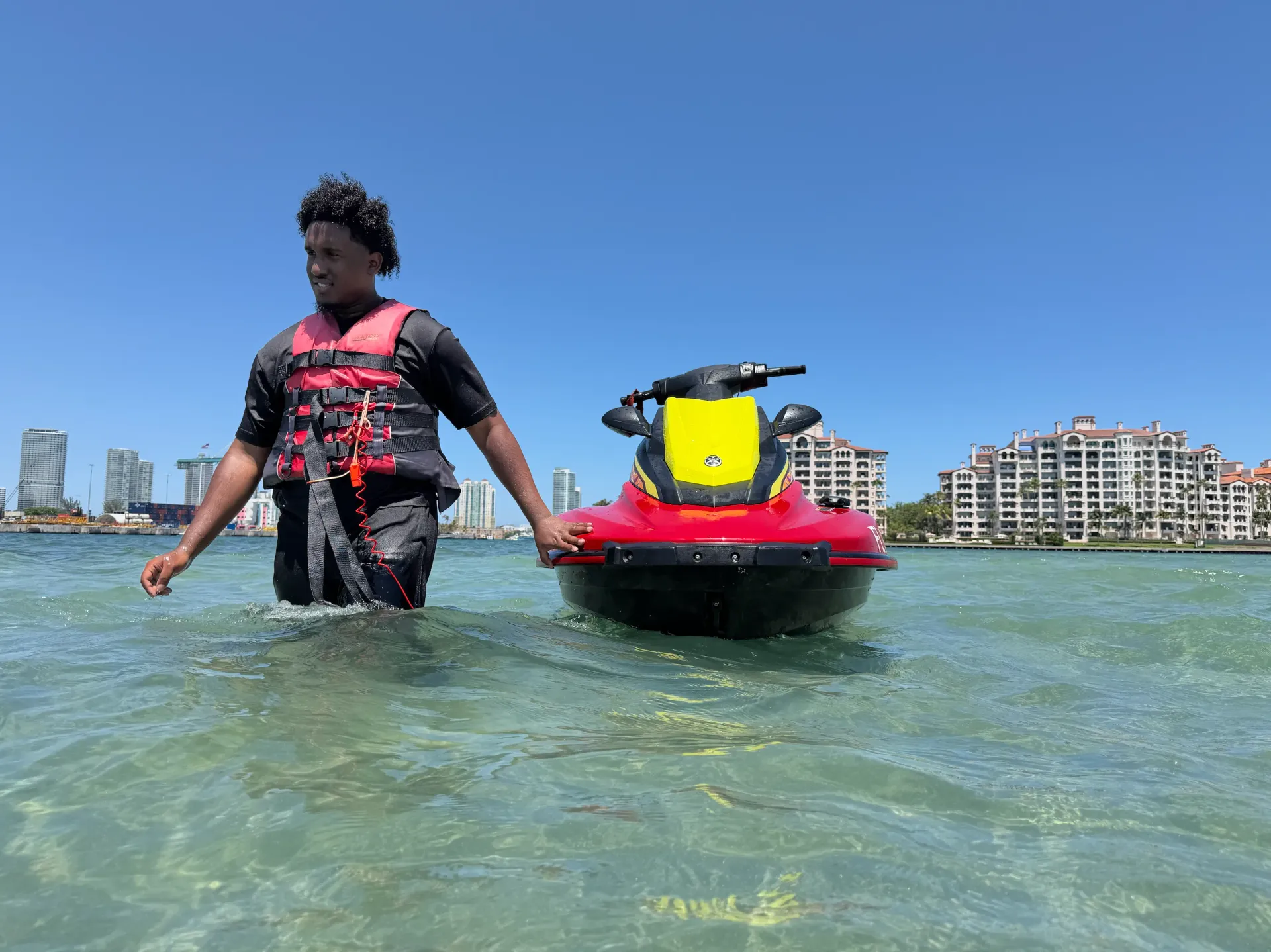 Guest standing beside a jet ski in the shallow waters near Fisher Island Sandbar on Biscayne Bay