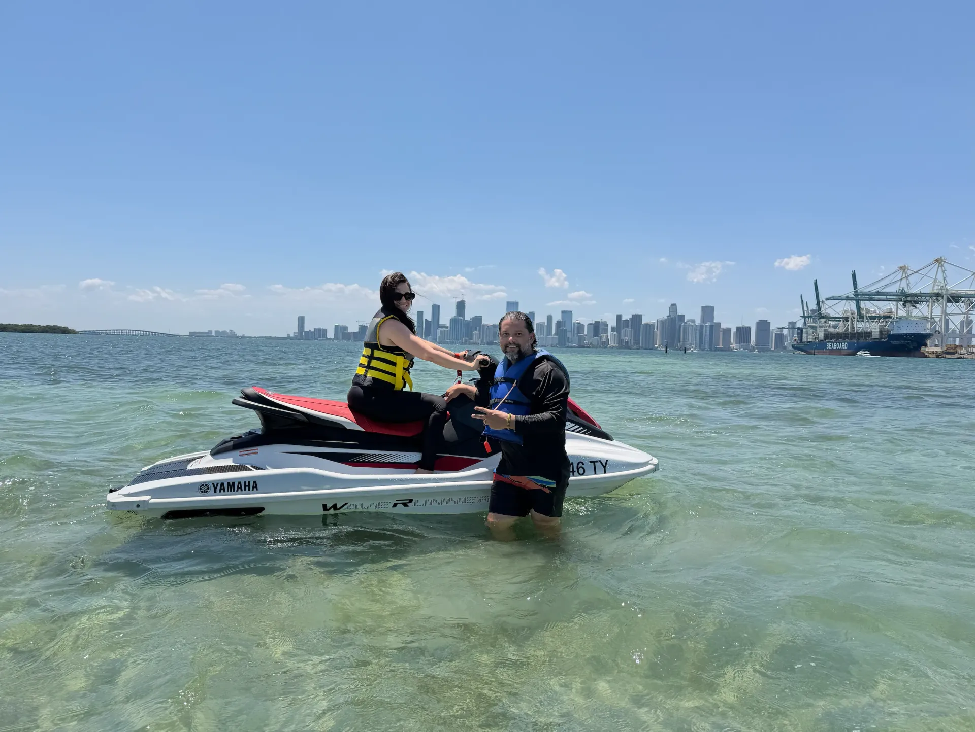 Couple enjoying a Romantic Jet Ski Tour in Miami at the Fisher Island Sandbar with the Downtown Miami skyline behind them