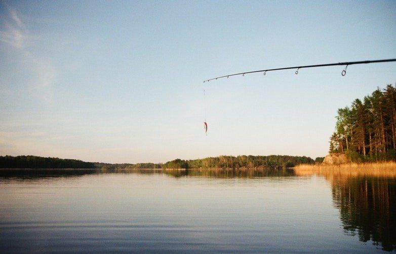 A person is fishing on a lake with a fishing rod.