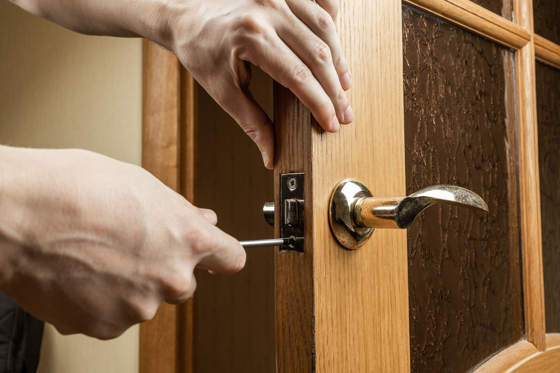 A locksmith is repairing a wooden door lock in an apartment for safety. A locksmith is repairing a wooden door lock in an apartment for safety.