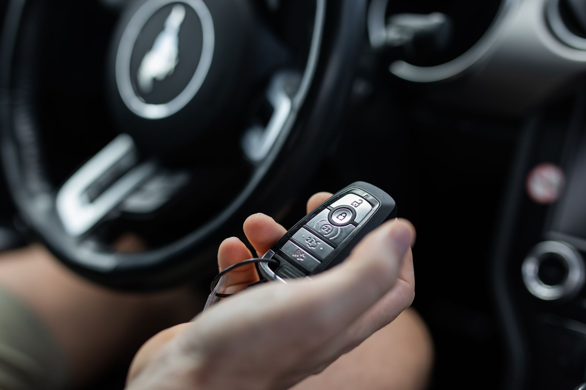 Person holding a car fob key while sitting inside a vehicle.