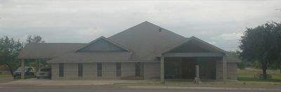 Single-story beige community building with a covered entrance on a cloudy day