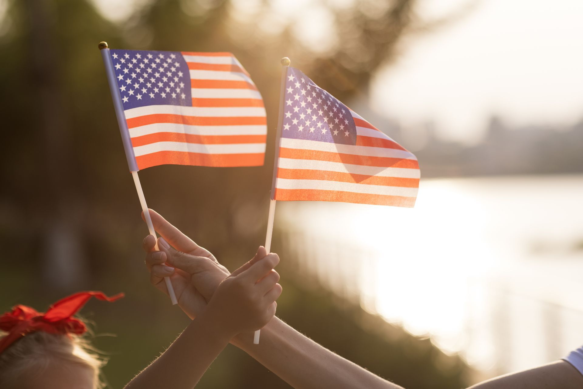 A man in white gloves is holding an american flag in front of a woman.