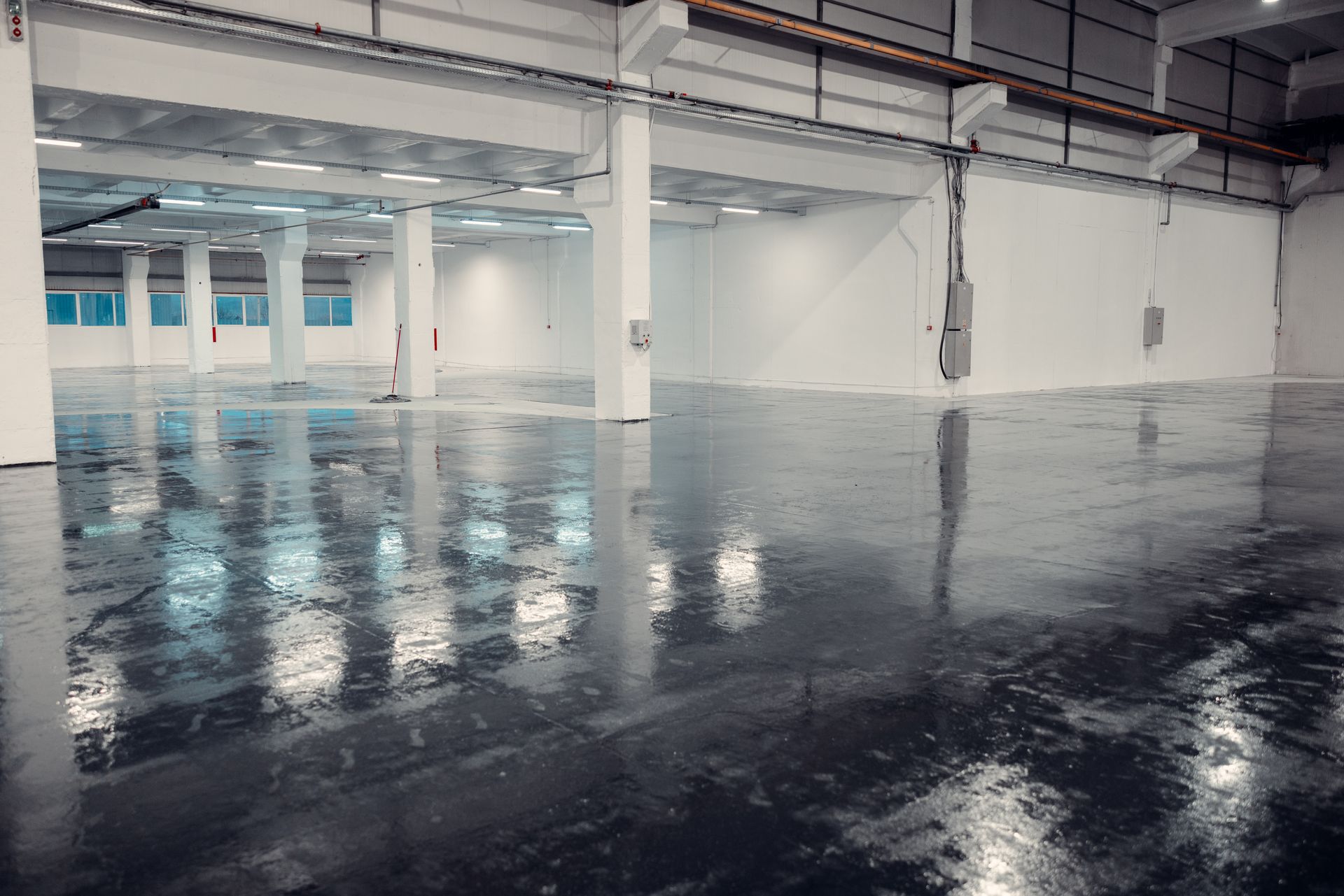 Empty glossy parking garage with white pillars and reflective black floor