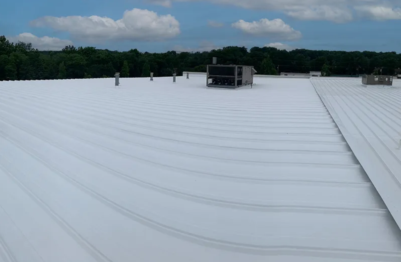 White commercial rooftop with HVAC units under a cloudy sky.