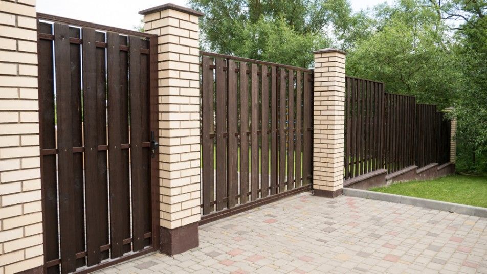 A Wooden Fence is Surrounded by Brick Pillars and a Brick Driveway — Harbour Fencing In Moonee Beach, NSW