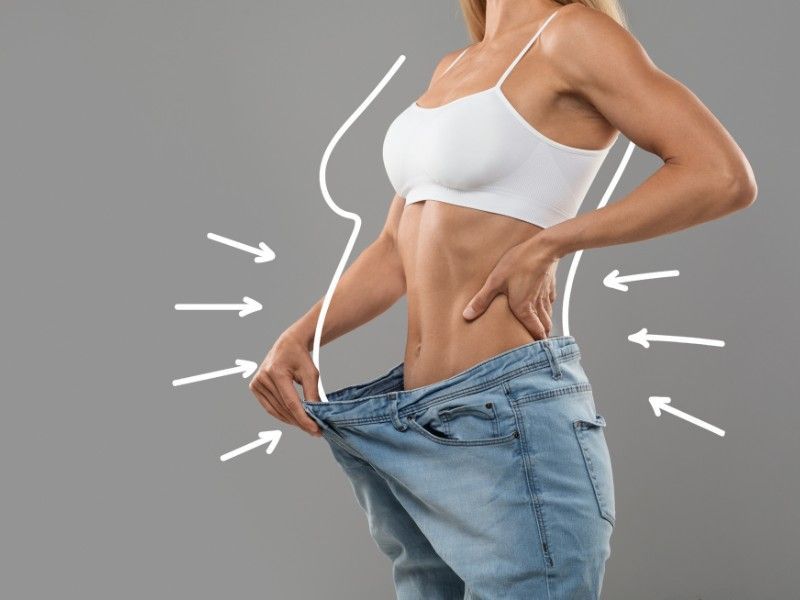 Uma mulher está vestindo um sutiã branco e jeans azul.