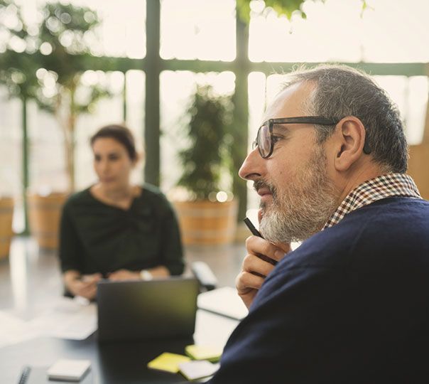 A man and a woman are sitting at a table with a laptop.