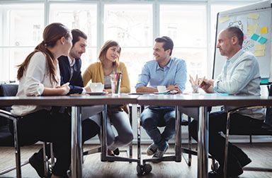 A group of people are sitting around a table having a meeting.