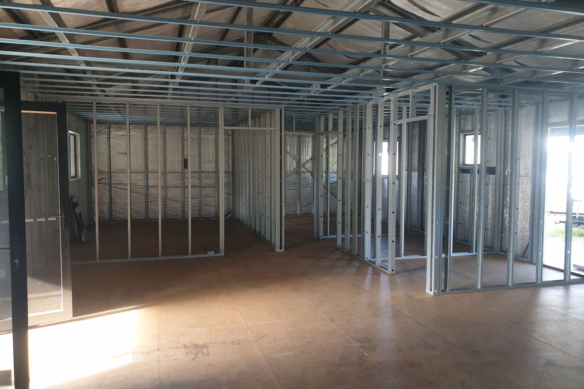Interior of a building under construction, showing metal stud framing for walls and ceiling — Steel Homes Australia in Branyan, QLD
