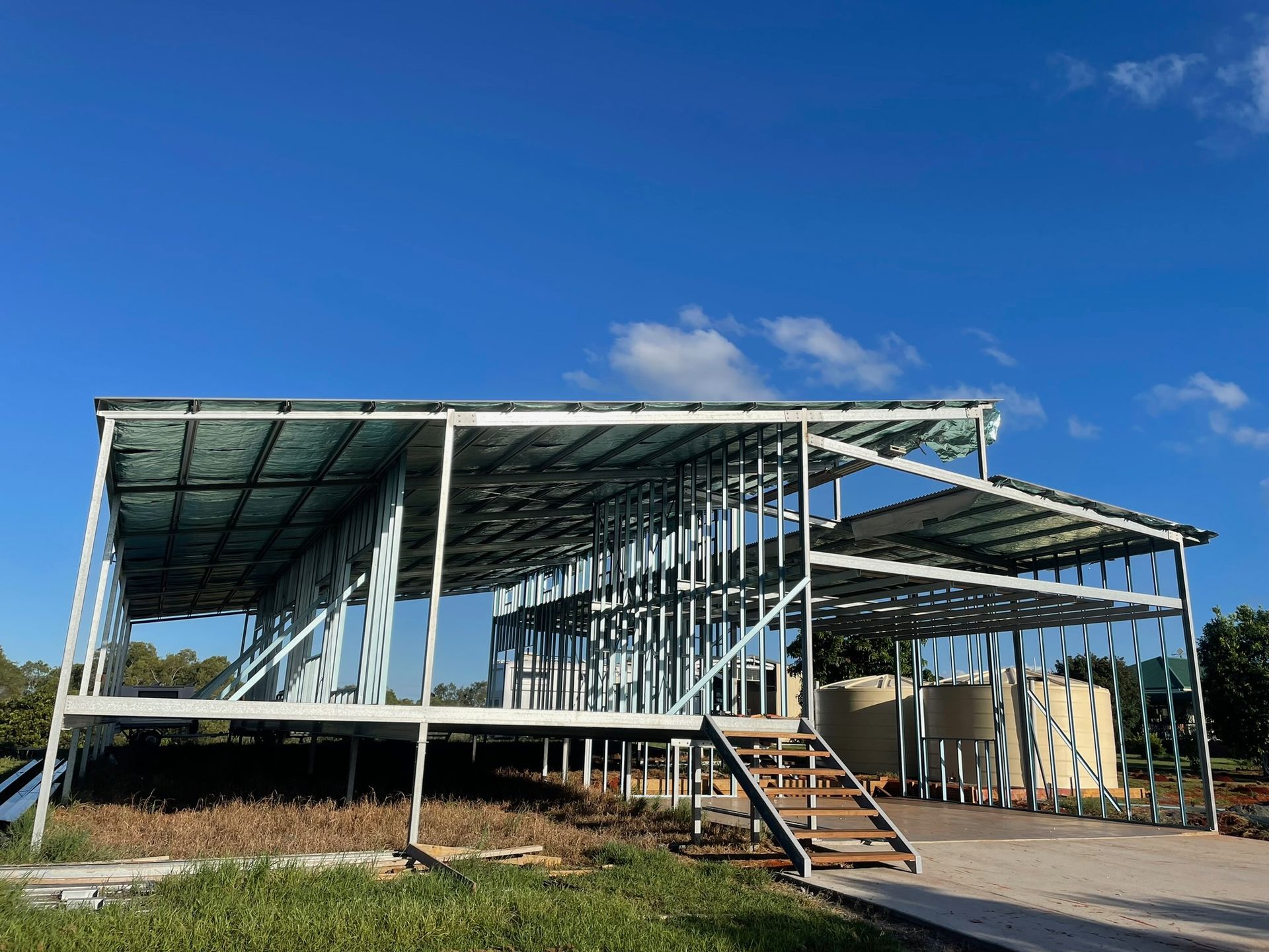 Construction site: Blue steel frame of a building against a cloudy sunrise — Steel Homes Australia in Branyan, QLD