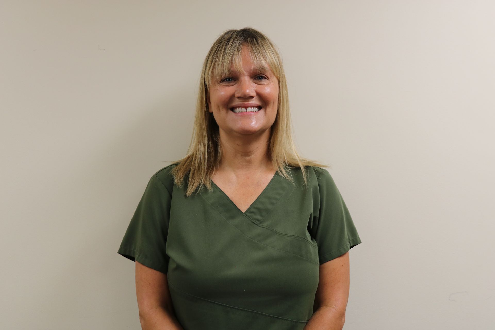 A woman wearing green is smiling for the camera.