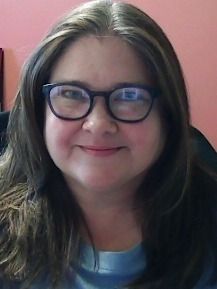 A woman wearing glasses smiling for the camera.