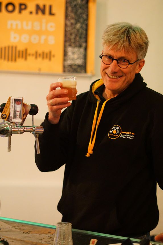 Lachende man in een zwarte hoodie met een glas bier van de tap.