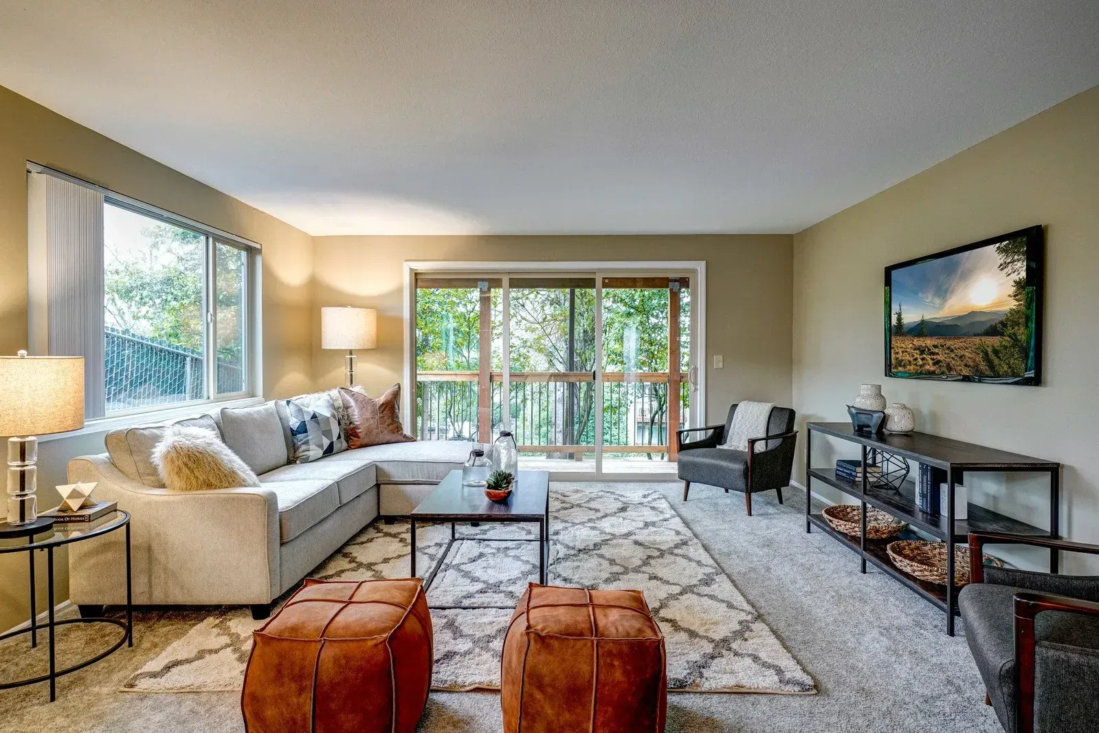 Living room with sectional sofa, rug, and sliding door to a wooded area.