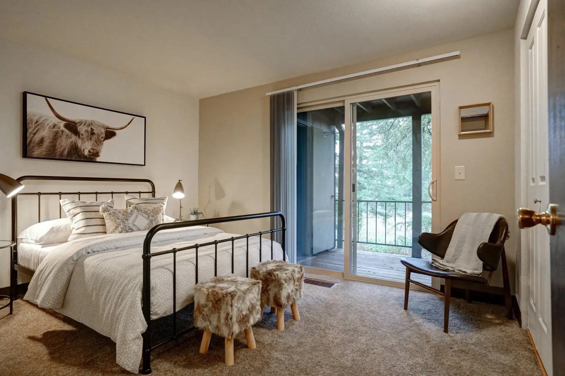 Bedroom with black metal bed frame, animal artwork, and sliding door to balcony.