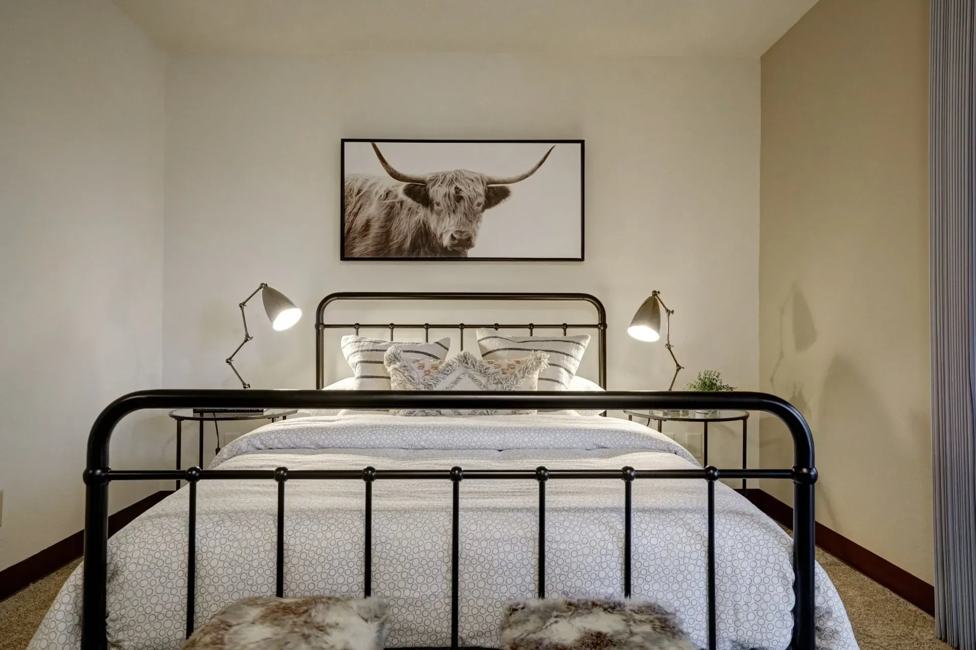Bedroom with black metal bed frame, animal print artwork, and matching lamps.