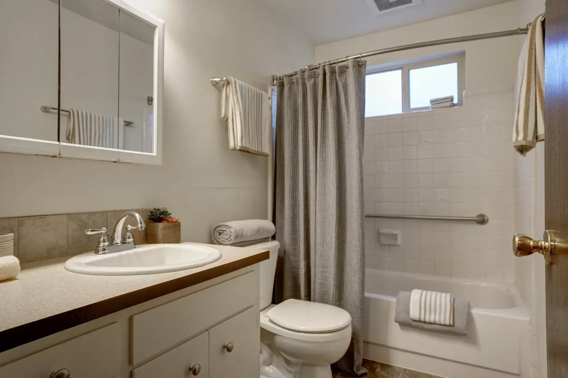 Bathroom with a toilet, sink, bathtub, and neutral color scheme.