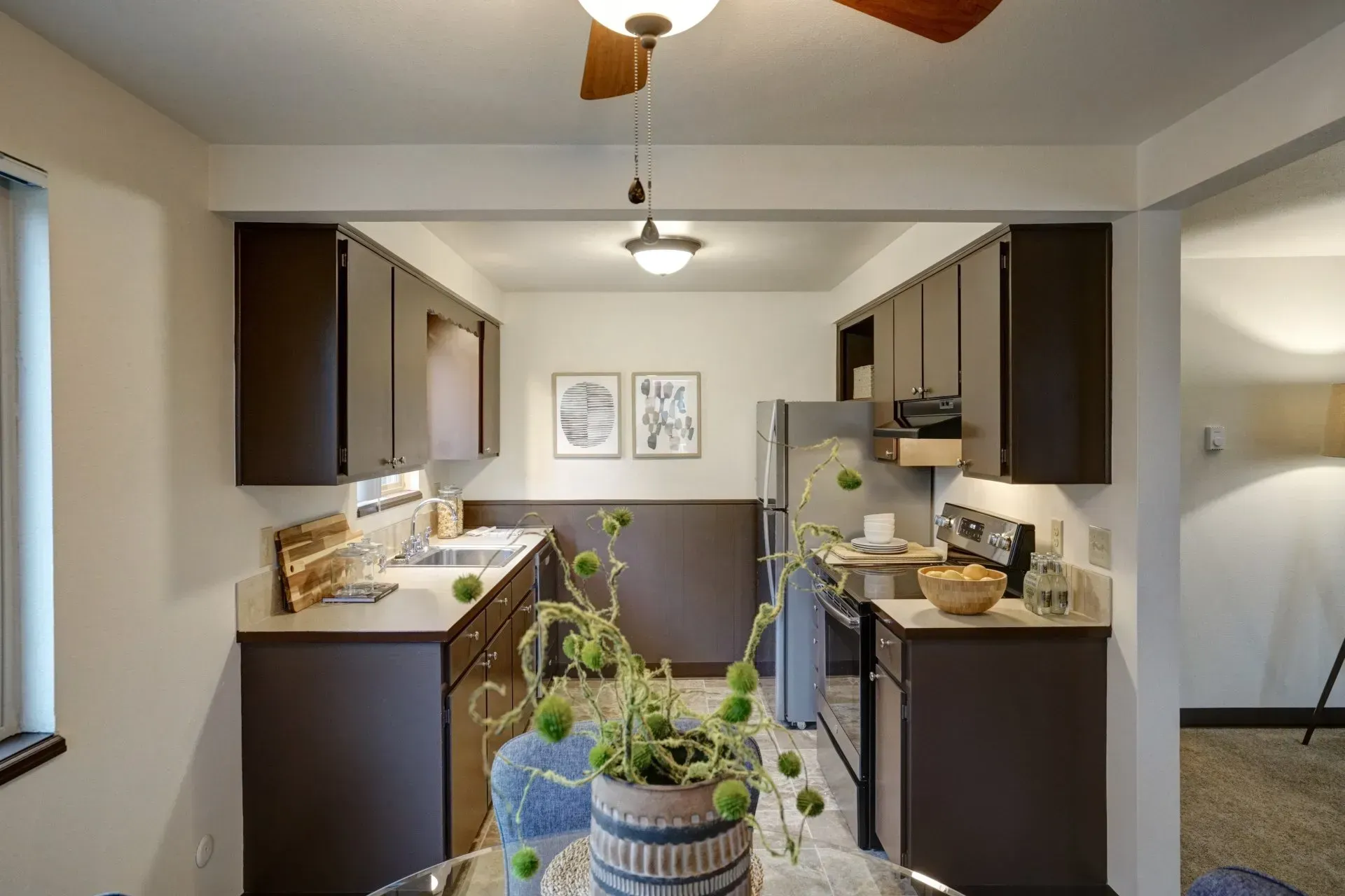 Kitchen with dark brown cabinets, stainless steel appliances, and white walls.