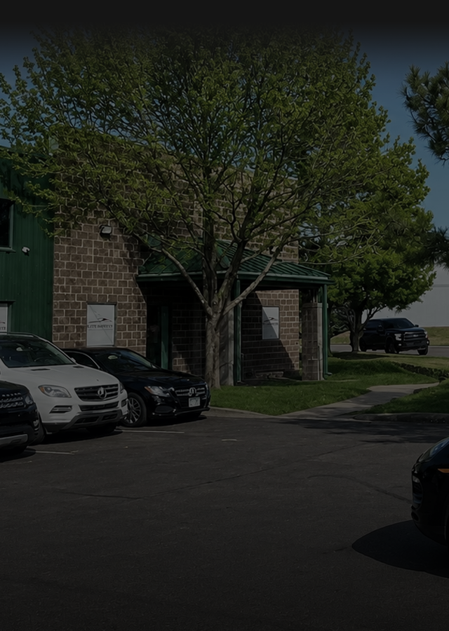 Parking lot by a building with parked cars, leafless trees, and a bright blue sky.