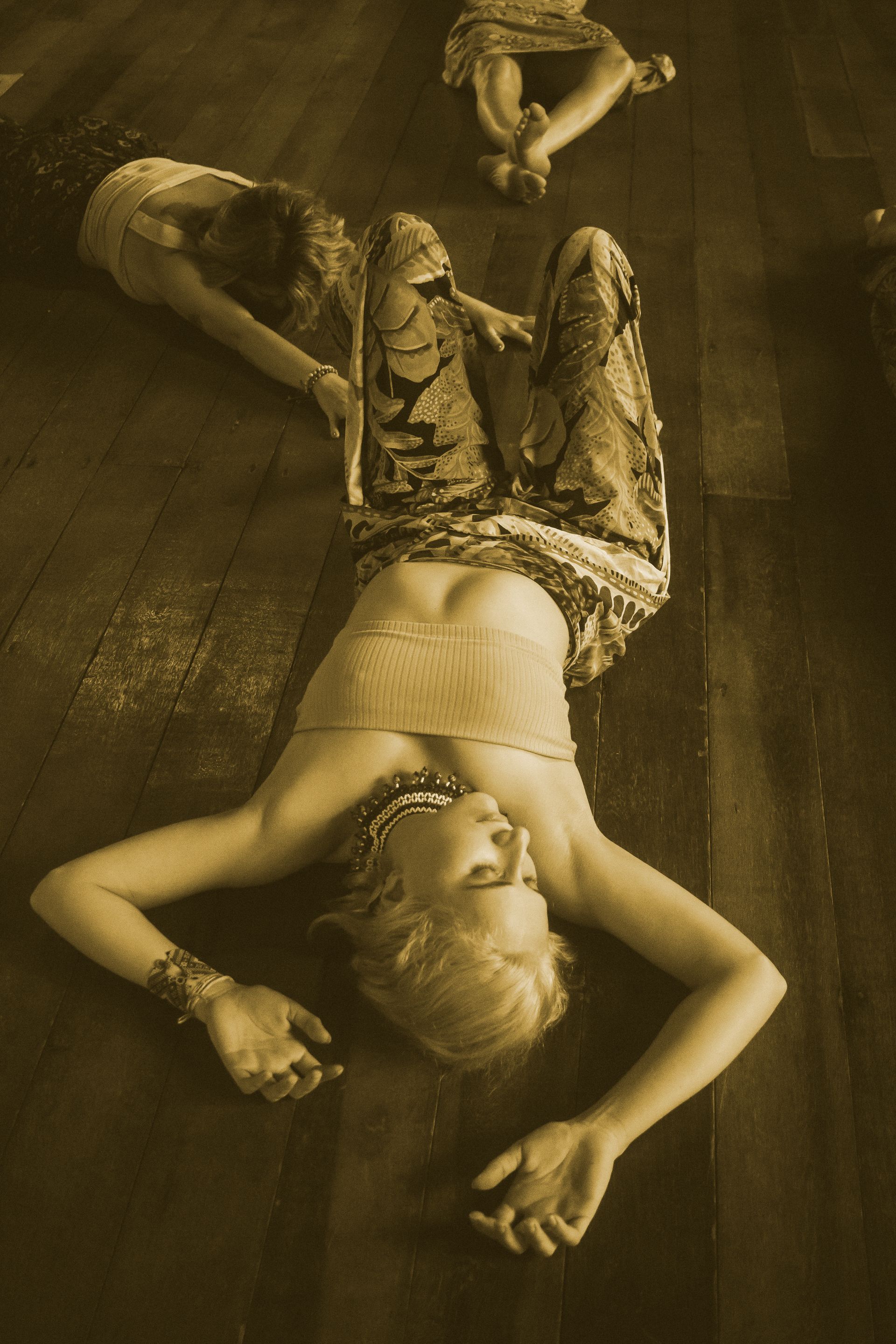 Mulher deitada em um piso de madeira em um retrato de estilo vintage em tons sépia.