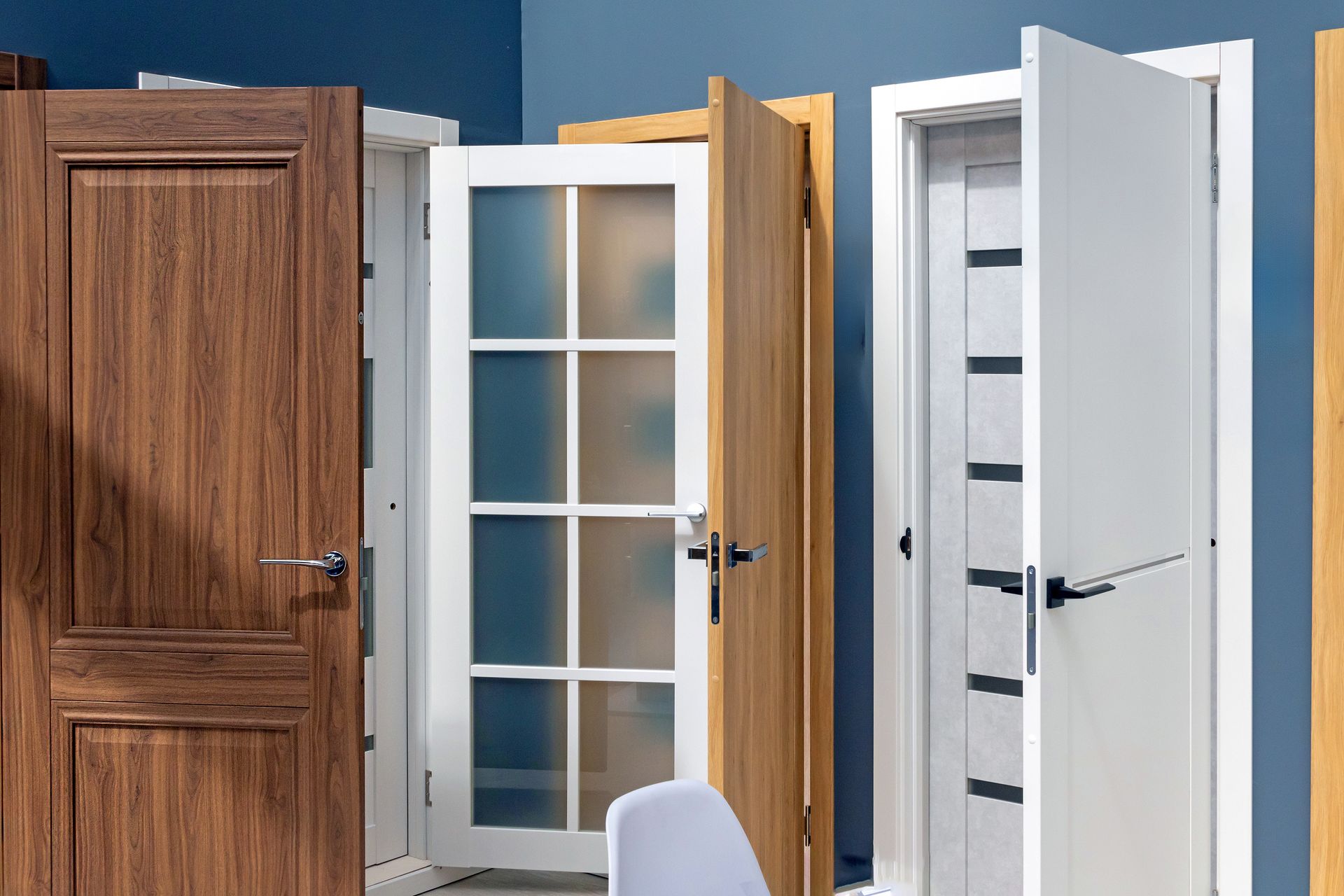 Showroom display of entry doors in wood-grain, glass-panel, and white finishes.
