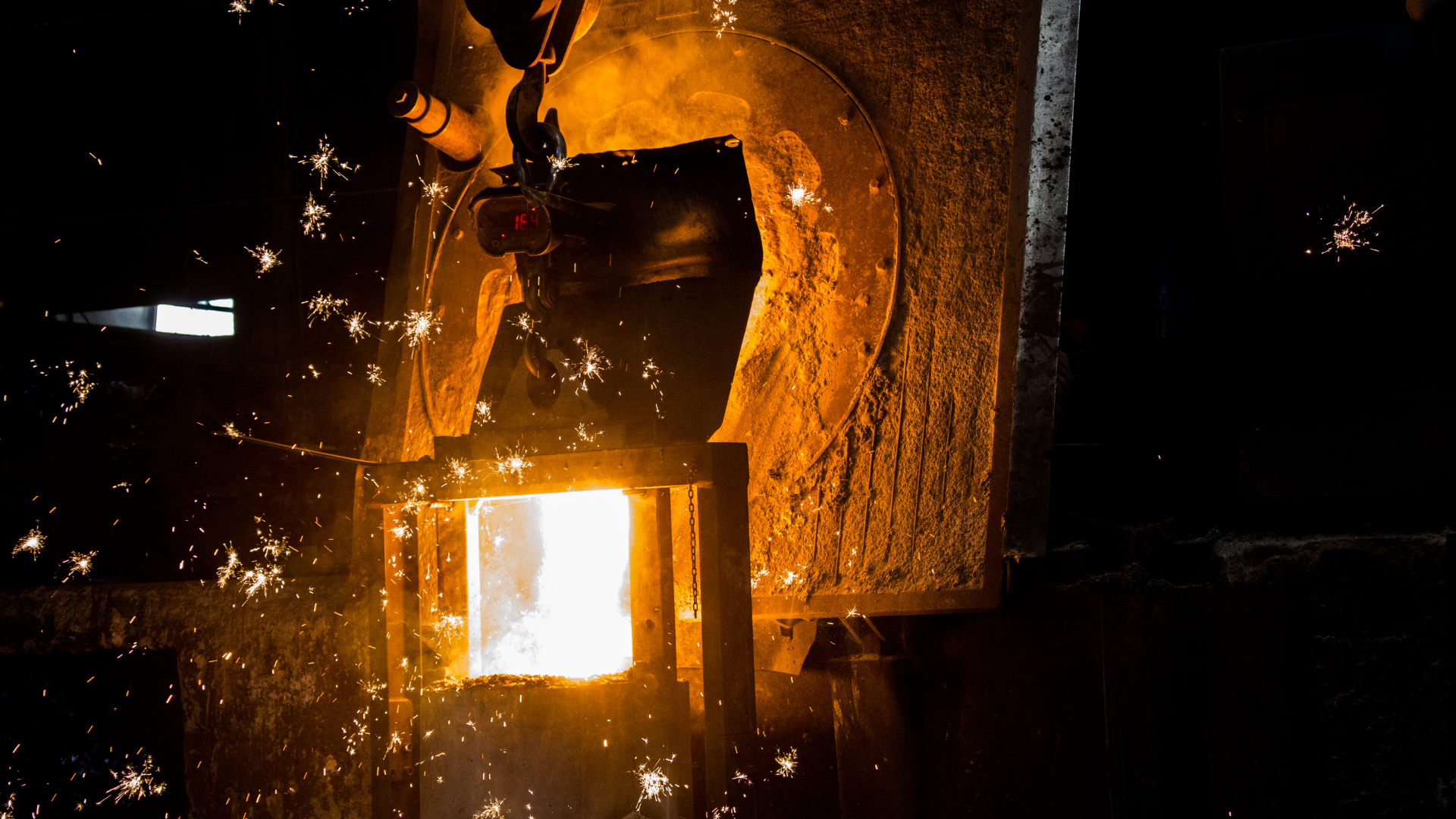 Welder in protective gear welding metal, blue sparks flying in an industrial workshop.